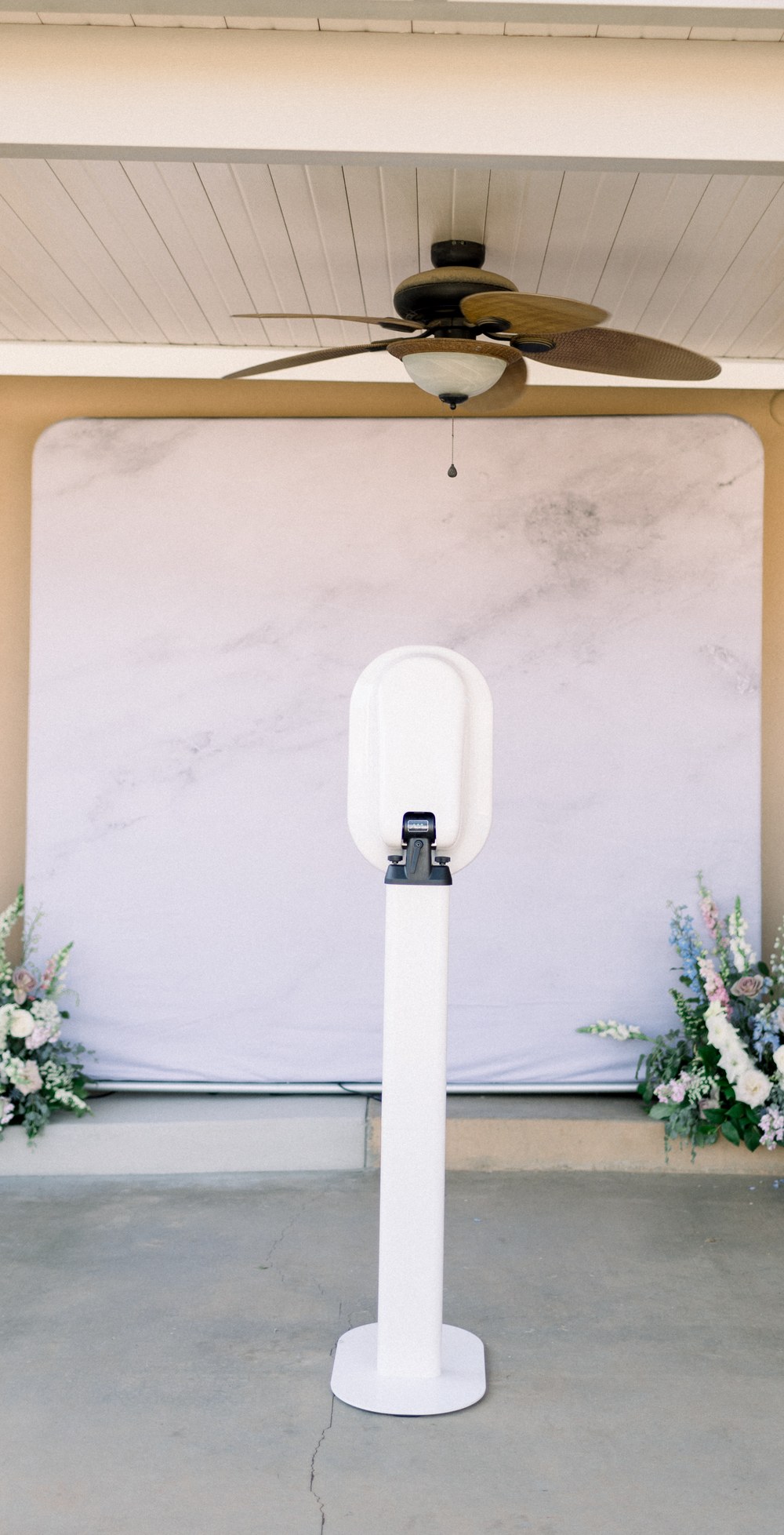 The booth set up under a covered patio against a white backdrop, with flower arrangements on either side