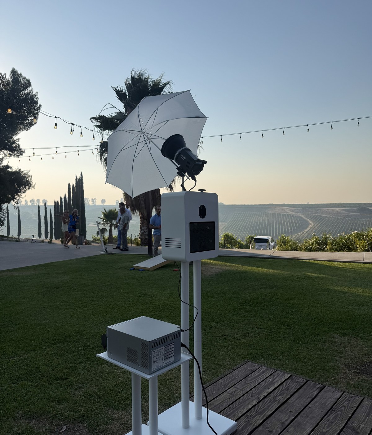 The photo booth set up outdoors on a deck at golden hour with string lights overhead