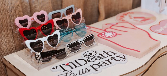 Prop sunglasses arranged on a riser beside a party sign