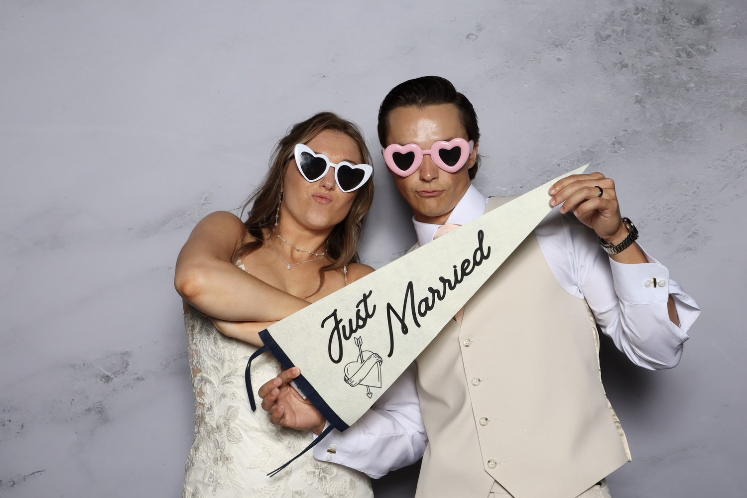 A couple holding a Just Married pennant in heart shaped sunglasses