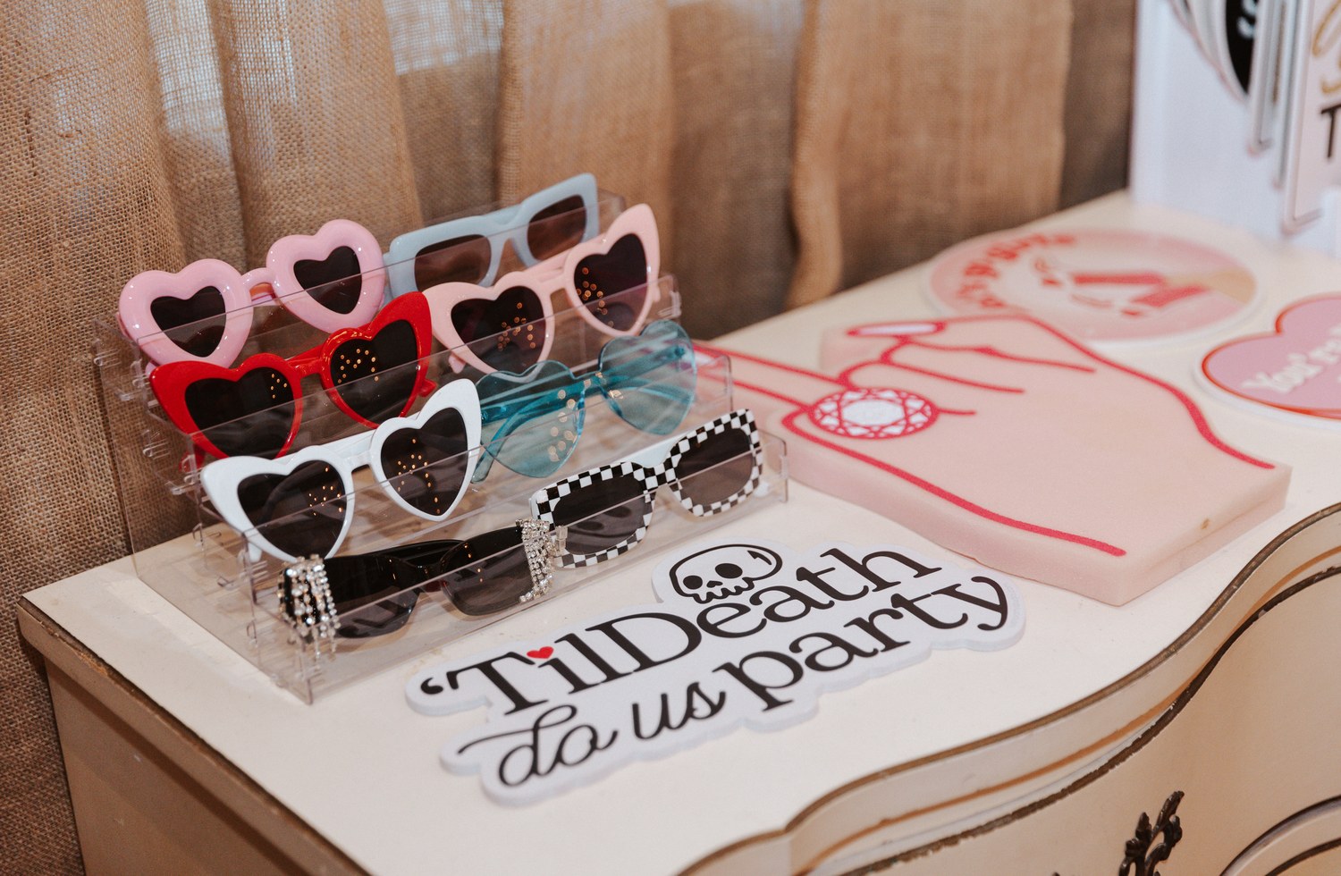 Heart shaped prop sunglasses on a riser beside a Til Death Do Us Party sign