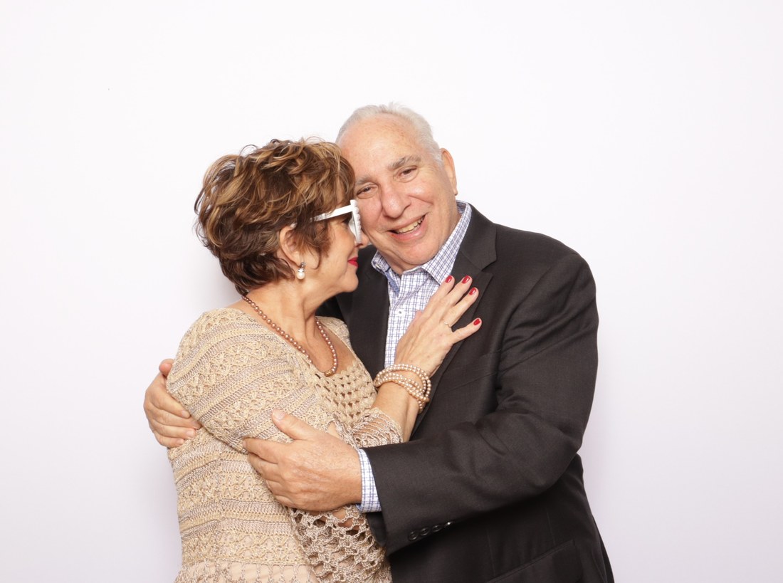 An older couple laughing together in front of a white backdrop under studio lighting