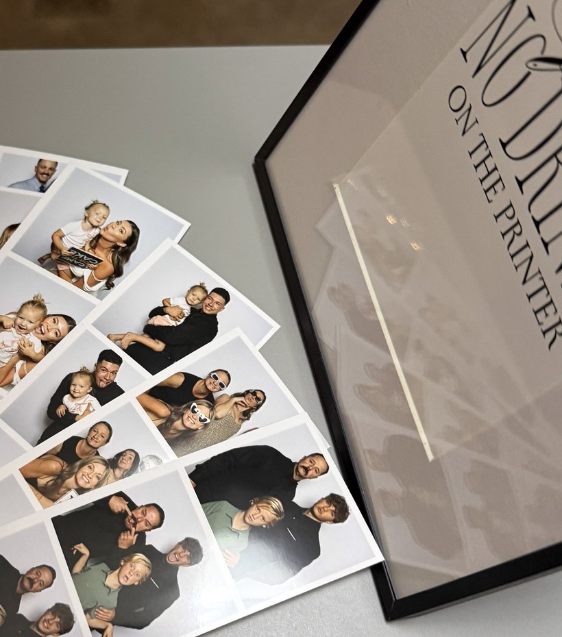 Printed photo strips fanned out beside a framed sign