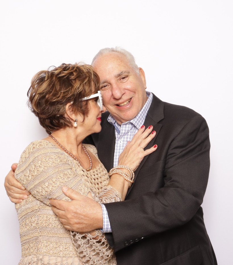 A couple hugging and laughing in front of a white backdrop