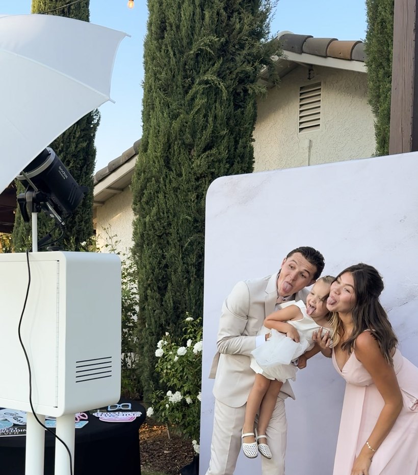The photo booth and lighting set up outdoors at a venue lined with cypress trees