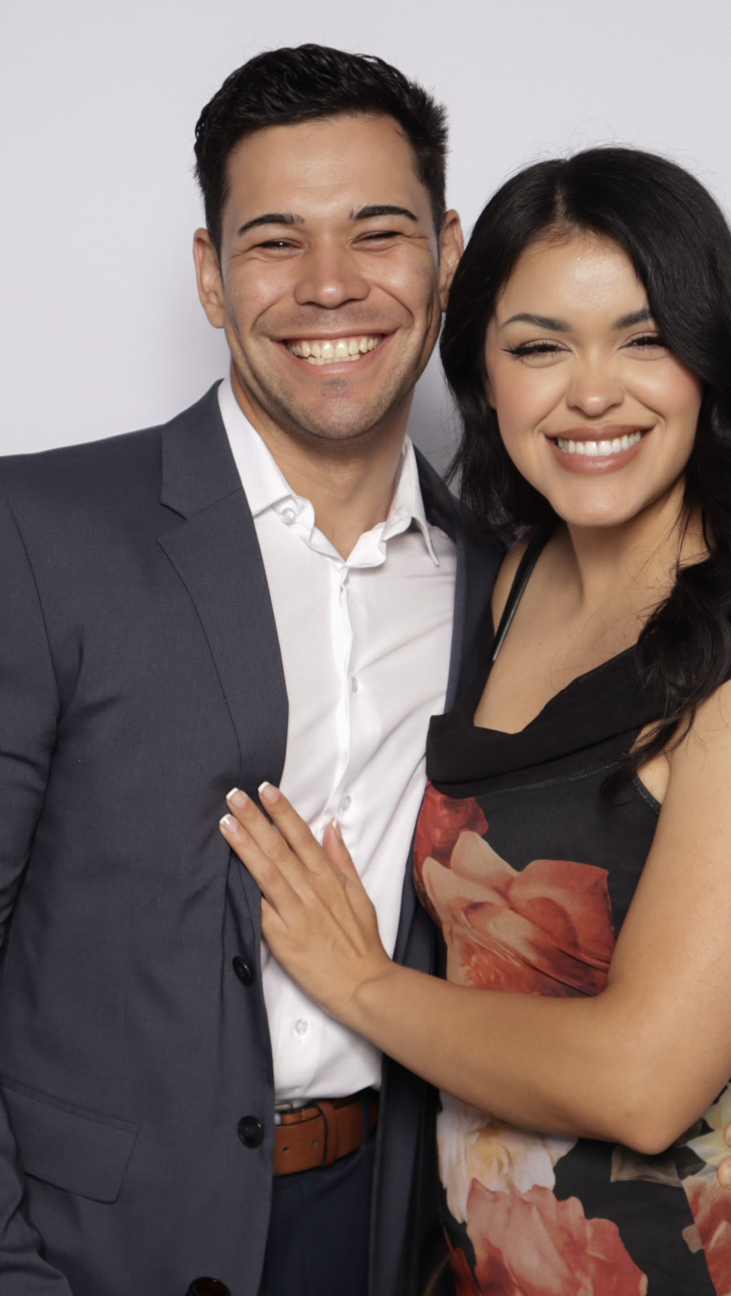 A couple posing together in front of a plain white backdrop under studio lighting