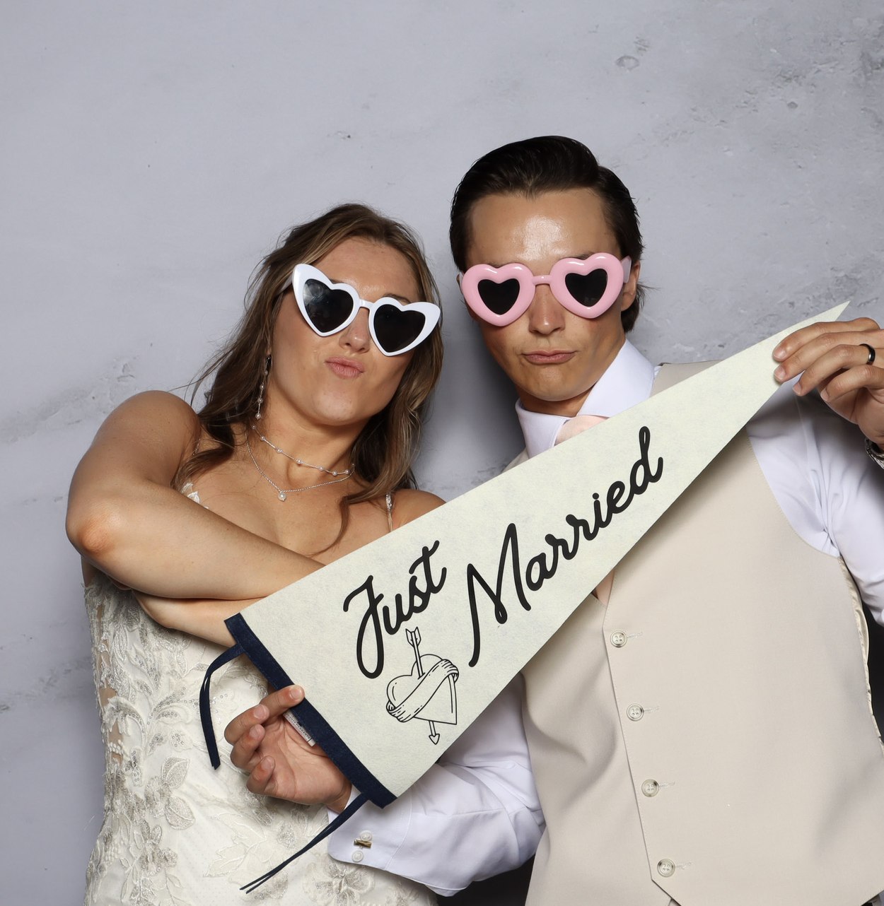 A couple holding a Just Married pennant in front of the marble backdrop
