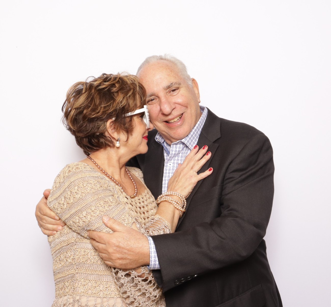 Two wedding guests hugging in front of a white backdrop